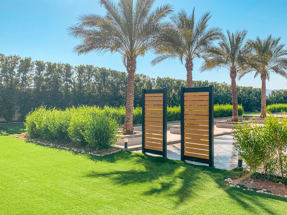 Stylish aluminum privacy screen with a wood-like finish in a sunny garden, providing a blend of elegance and functionality for outdoor spaces