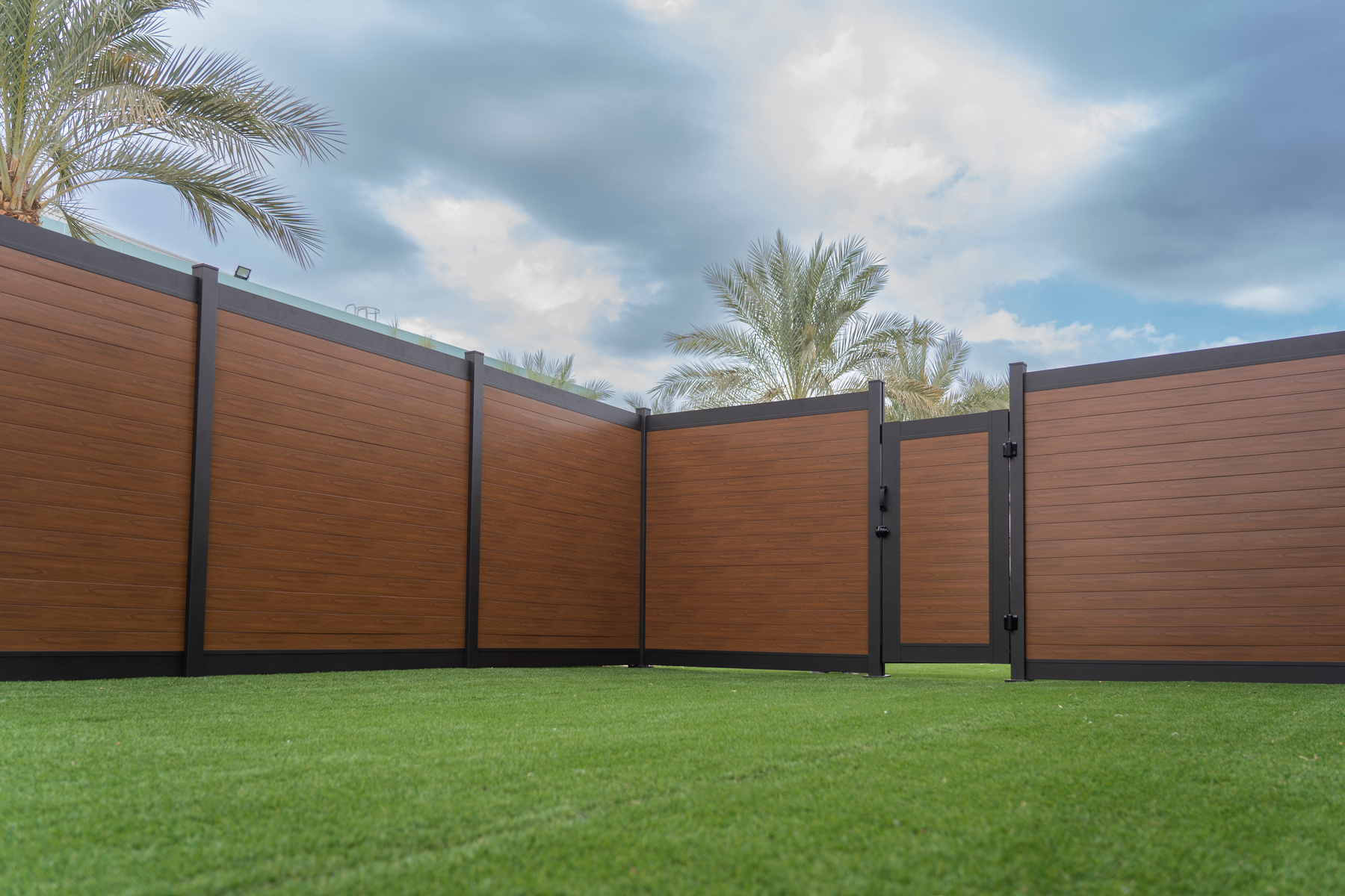 Modern aluminum gate with a wood-like finish, providing a stylish and secure entrance, surrounded by matching fencing