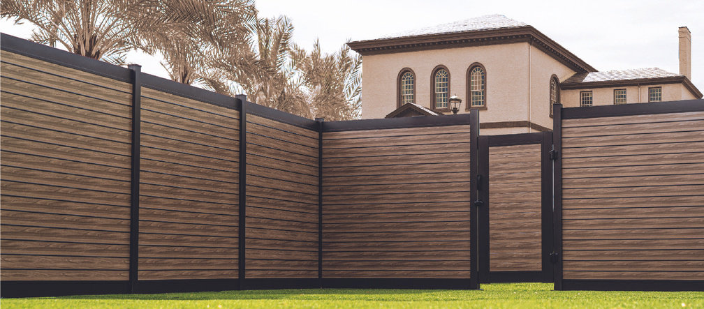 Elegant aluminum fence with a wood-like finish surrounding a Spanish-style villa, offering a stylish and durable fencing solution with palm trees in the background