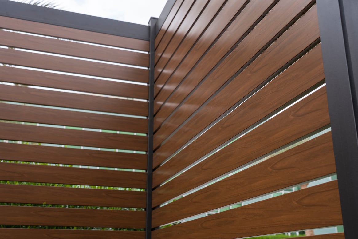 Close-up of aluminum fence panels with a wood-like finish, highlighting the realistic texture and modern design for stylish residential fencing solutions.